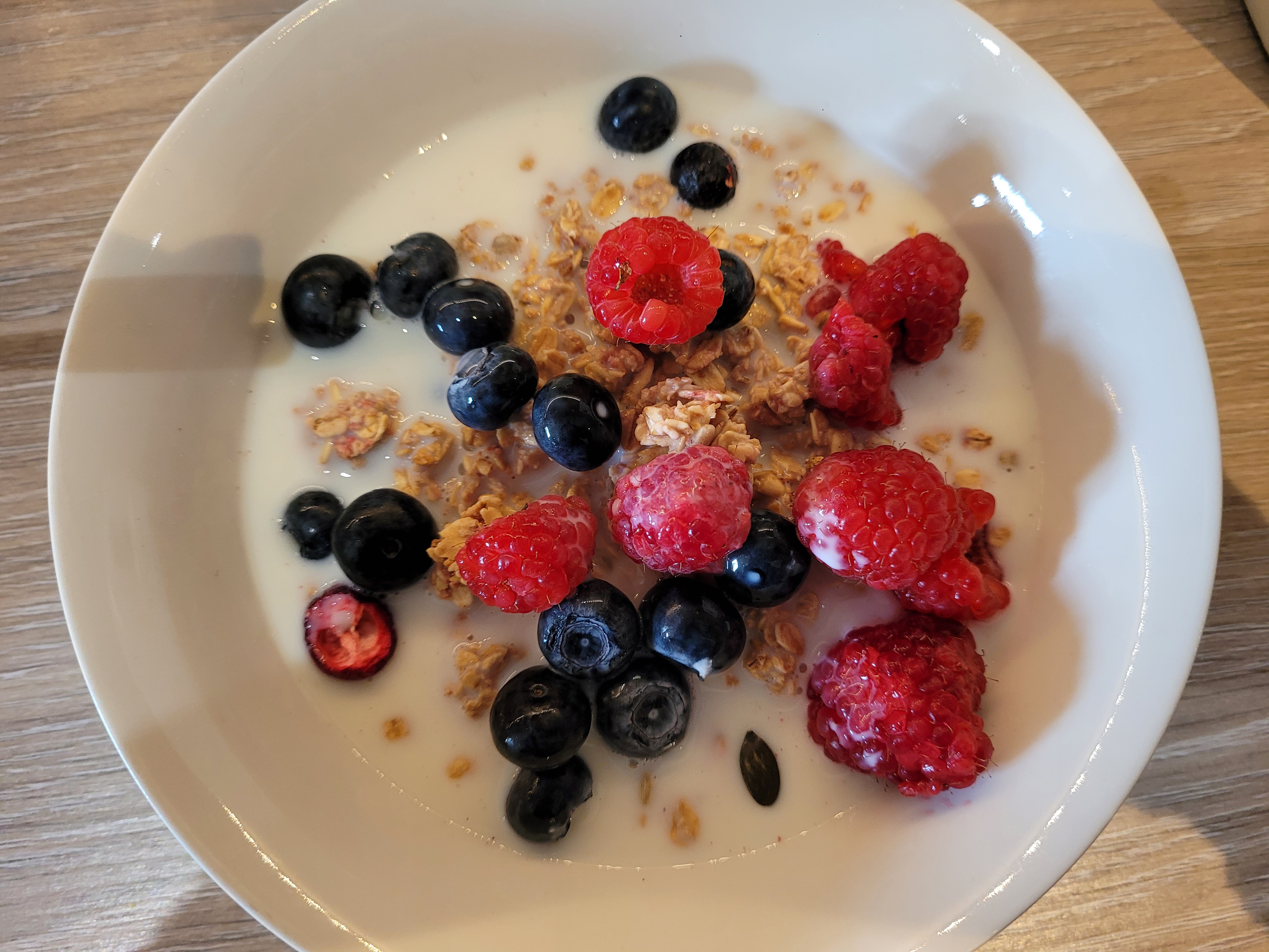 Breakfast granola, blueberries, raspberries and milk